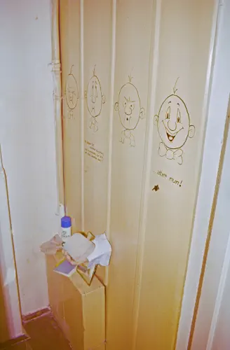 Blick auf eine bemalte Holzwand, es sind vier karrikierte Gesichter zu sehen,
die ersten drei sund verkniffen, das letzte lacht